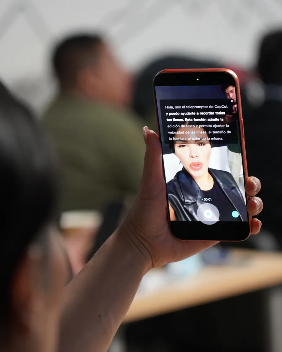 Celular mostrando un teleprompter mientras una alumna graba contenido